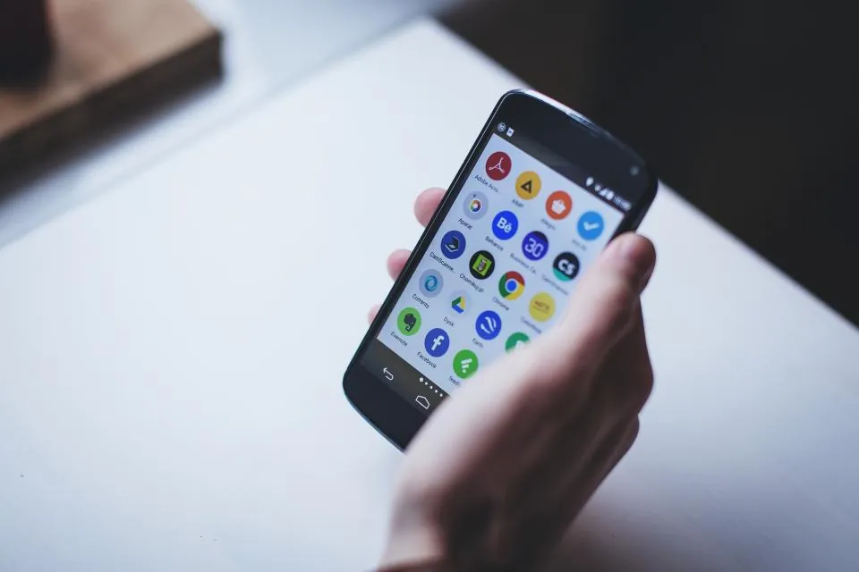Hand holding a smartphone showing mobile apps