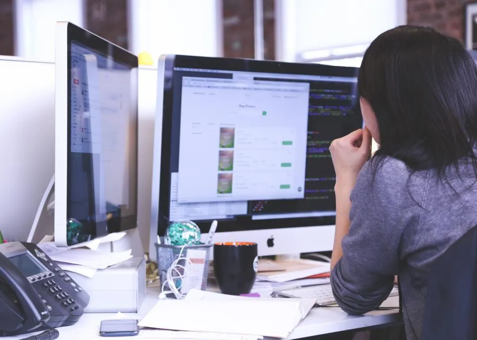 Software engineer working with code across two monitors