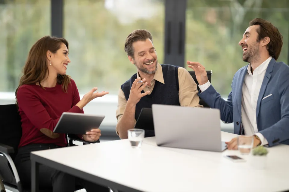 Team members discussing a project around a laptop and tablet in a bright office