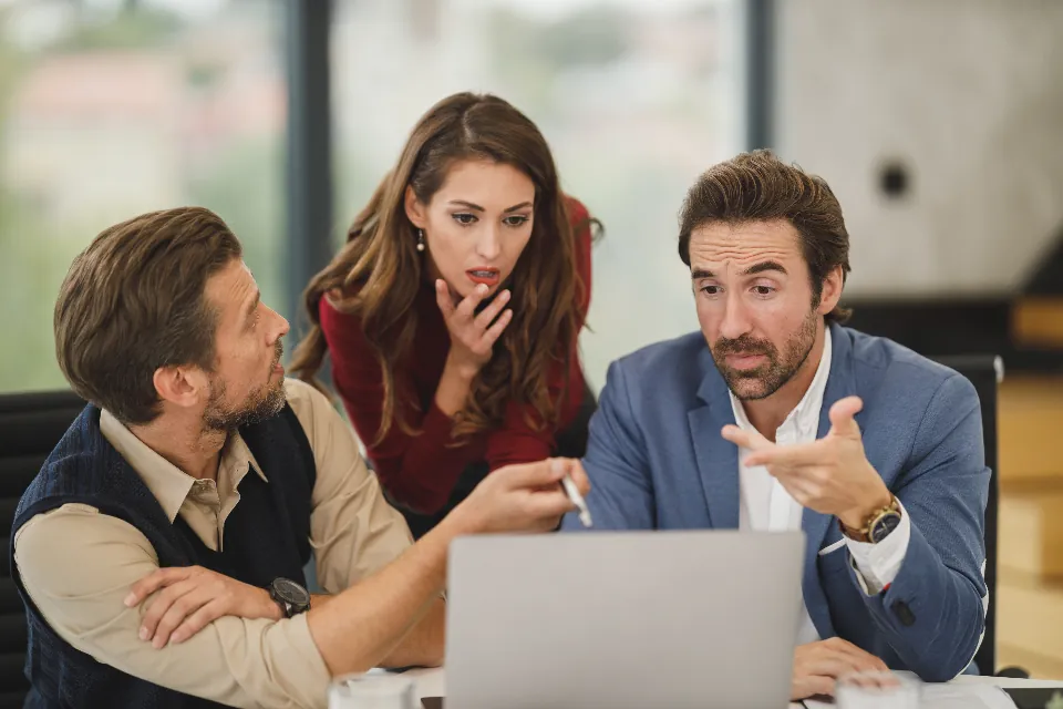 Three colleagues reviewing work together on a laptop